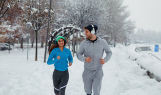Young Couple Running On A Snowy Day