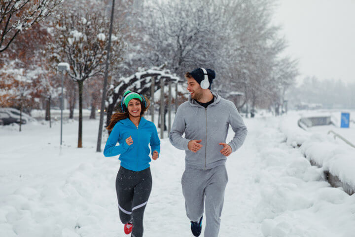 Young Couple Running On A Snowy Day